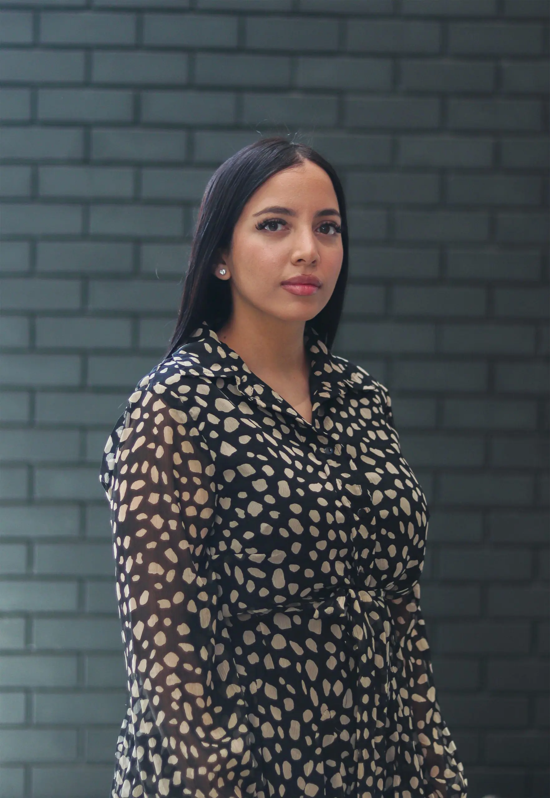 Shanon-Lee Davis standing in front of a dark brick wall